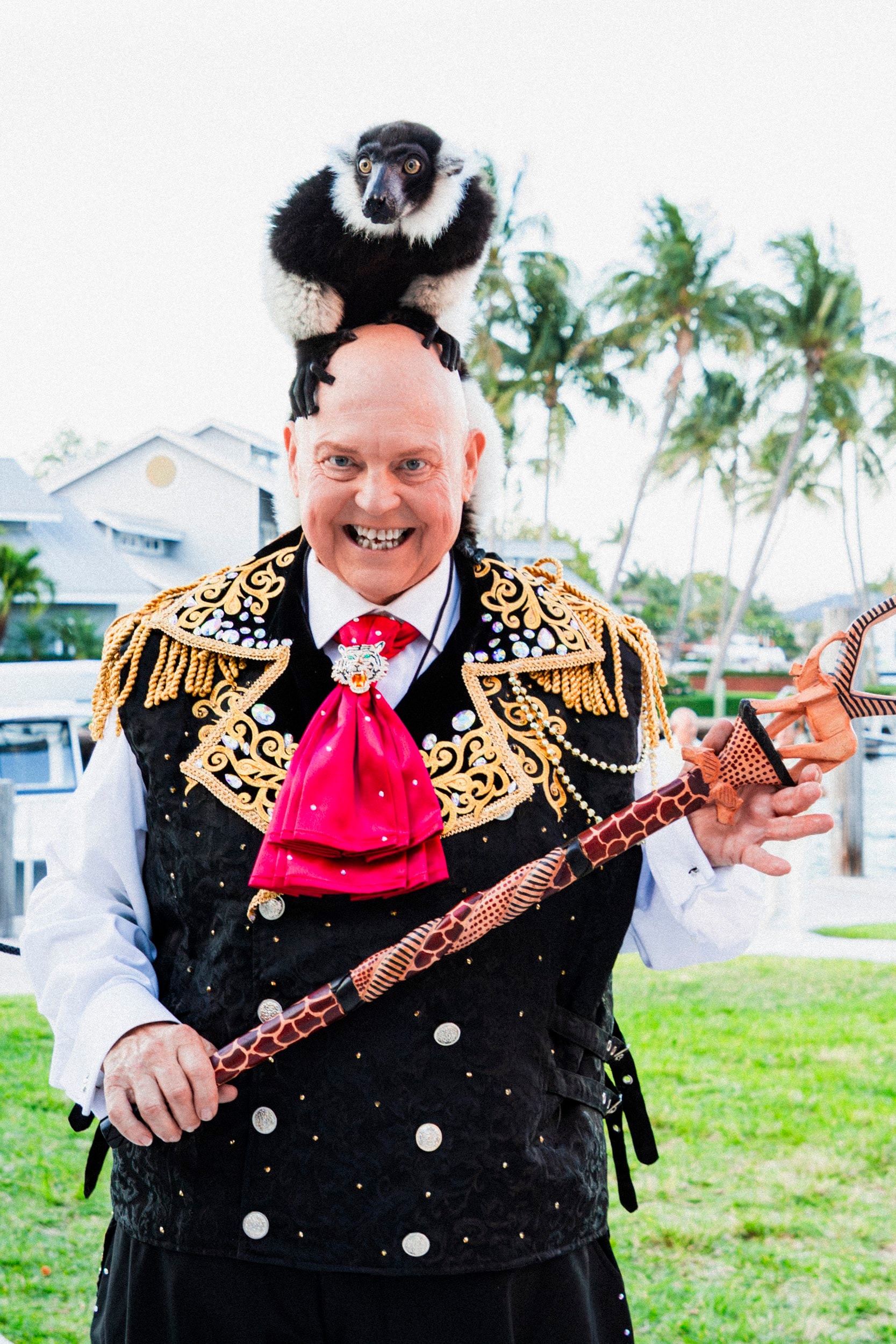 Man in ornate jacket holding lemur and staff