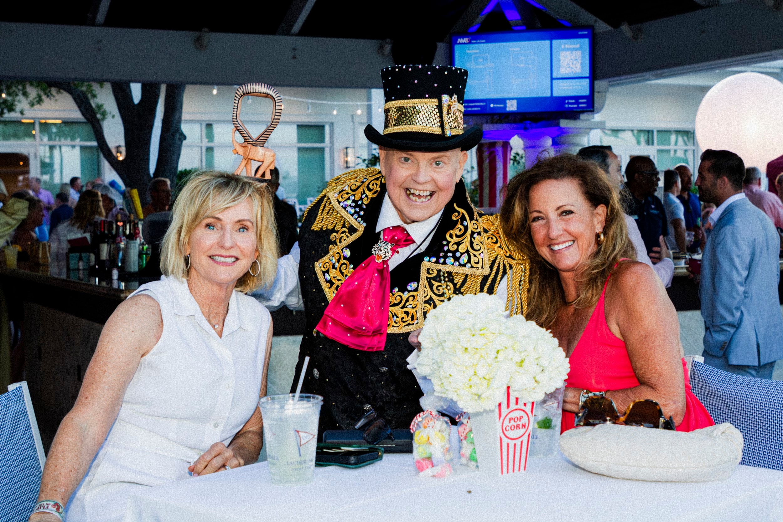 Man in sequined ringmaster costume with two women